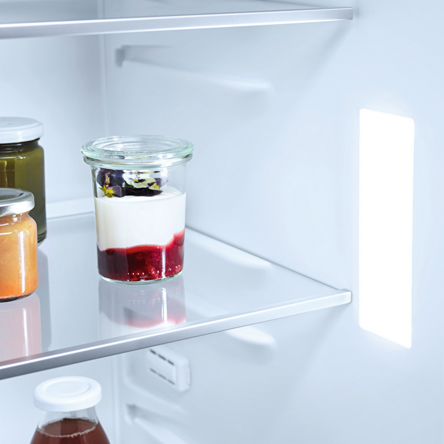 Im Inneren eines Kühlschranks, mit Gläsern Joghurt, Beeren und Saft.