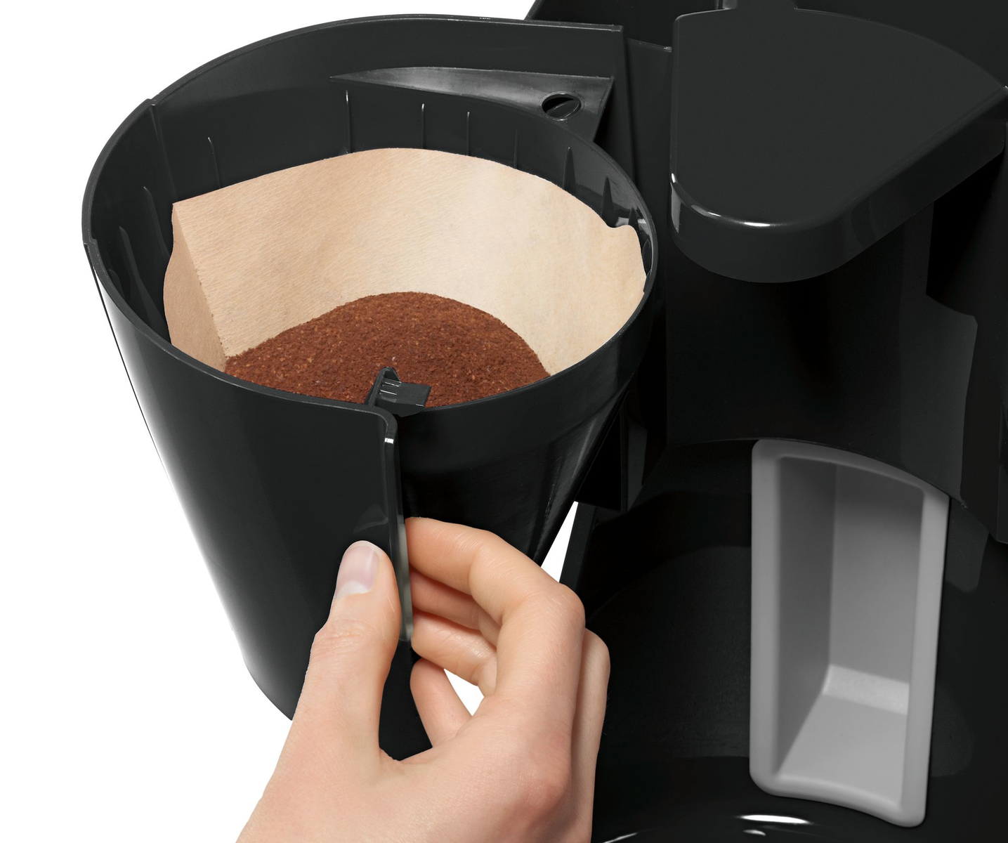 La mano di una persona che mette un filtro di carta con fondi di caffè in una caffettiera.