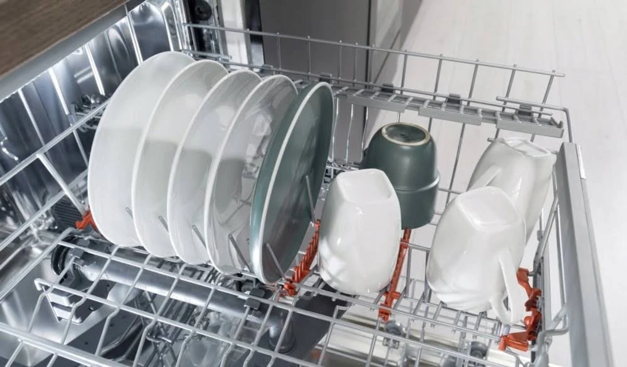 Rejilla de lavavajillas con platos y tazas. Platos apilados. Tazas en la rejilla.