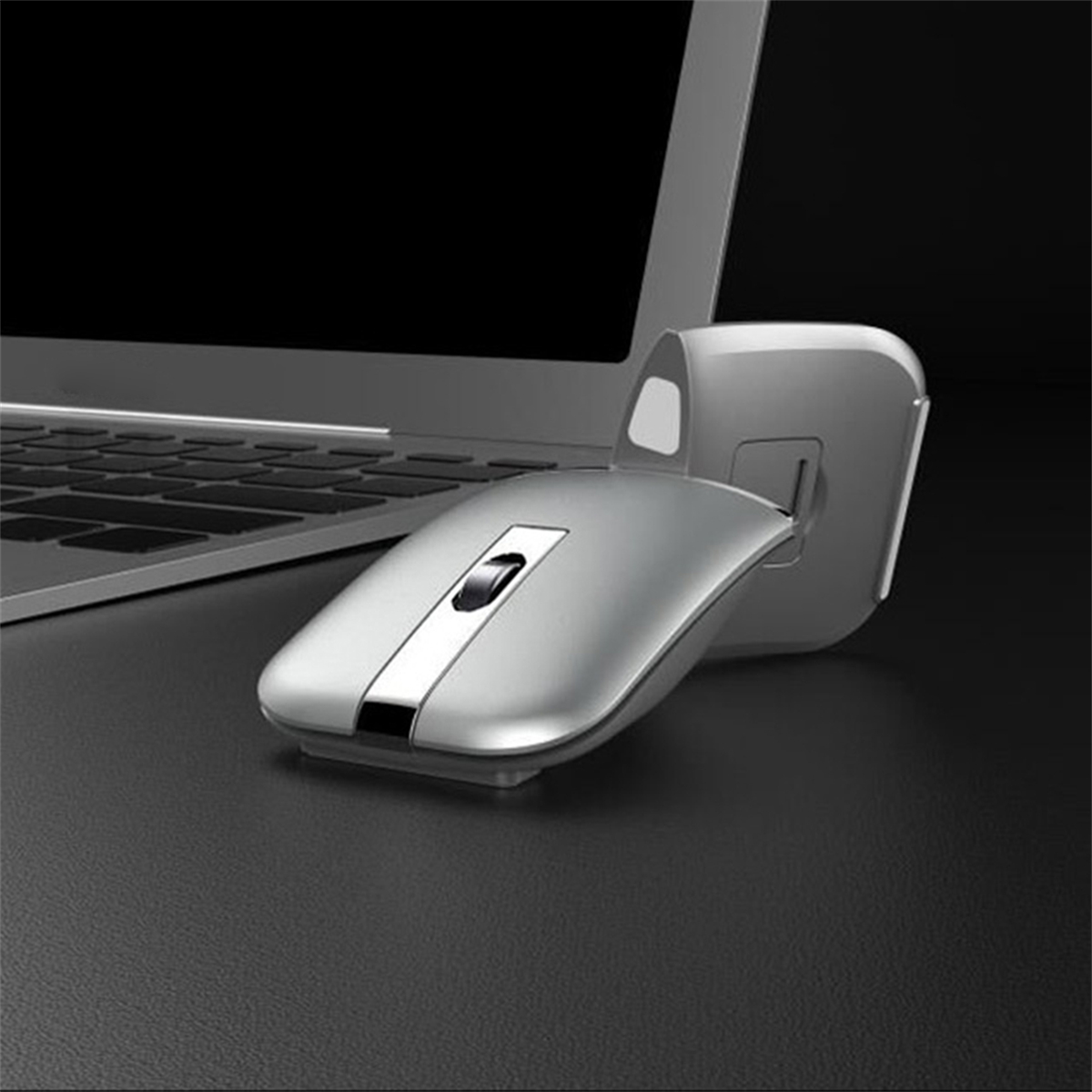 Silberne kabellose Maus, schwarze Oberfläche, gepaart mit einem Laptop, schwarzer Hintergrund.