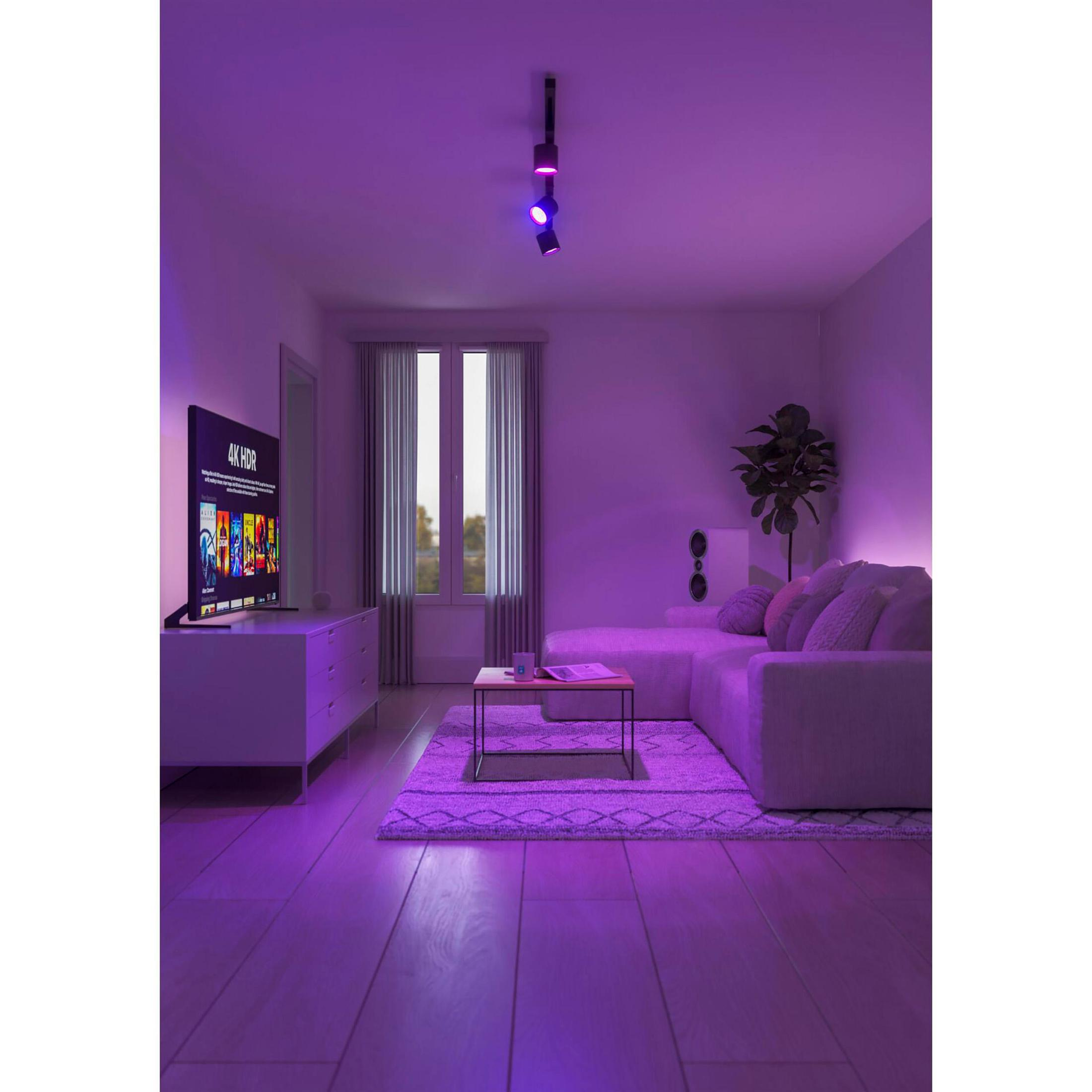 Scena di soggiorno con illuminazione viola, TV, divano e tappeto. Faretti.