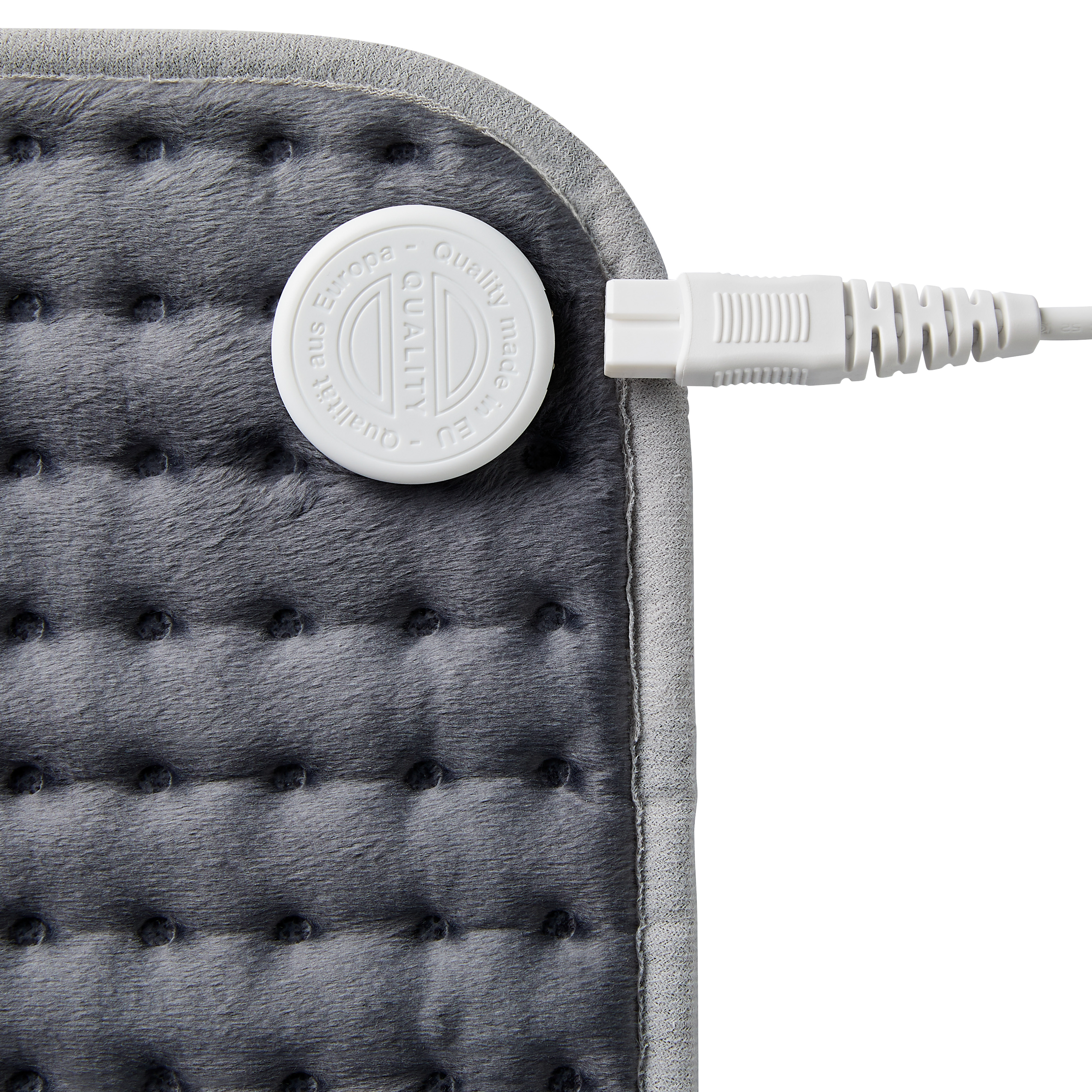 Gros plan sur un coussin chauffant gris avec un câble de connexion blanc. Le coussin a une commande ronde blanche.