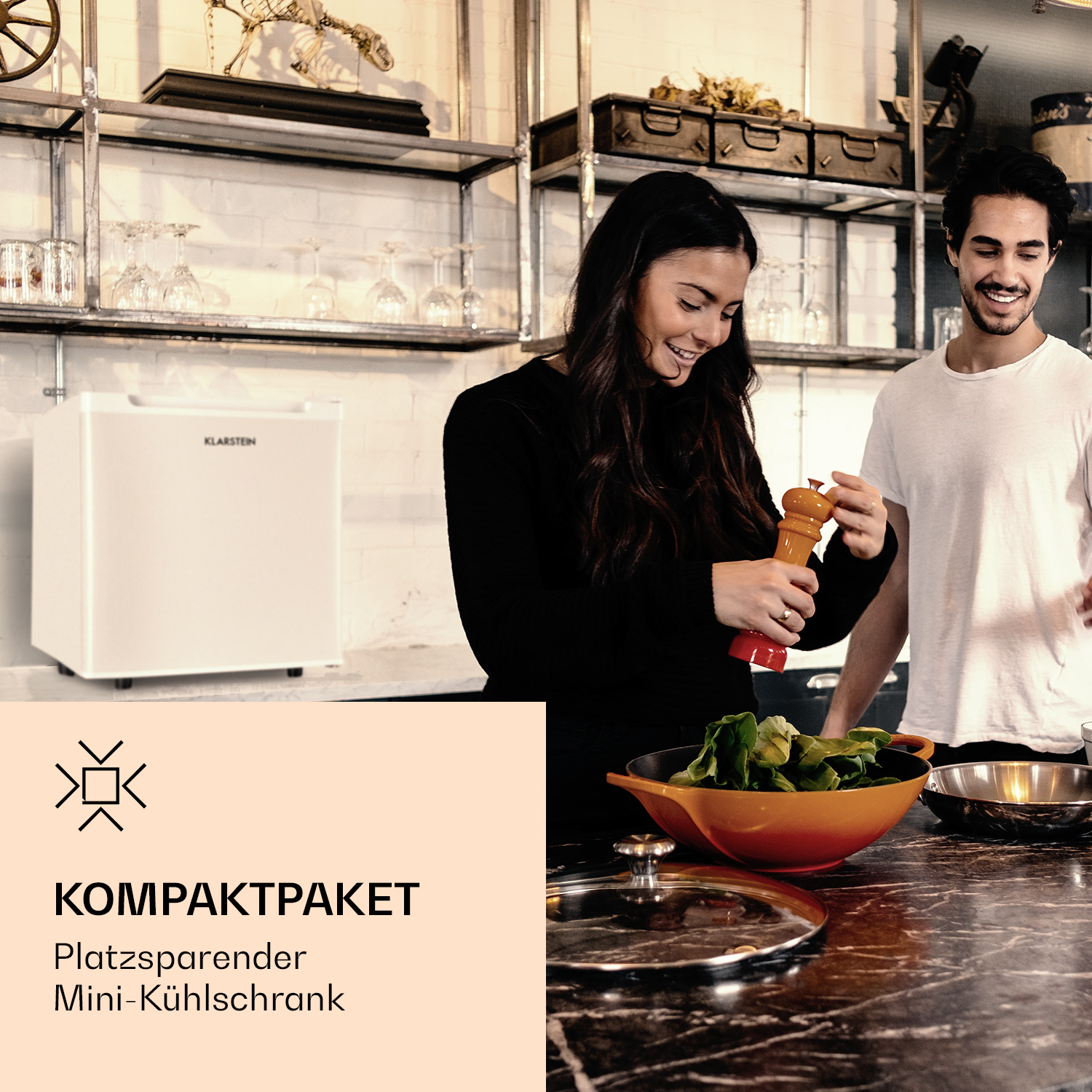 Una escena de cocina con una mujer usando un molinillo de pimienta. También hay una mini nevera y un hombre.