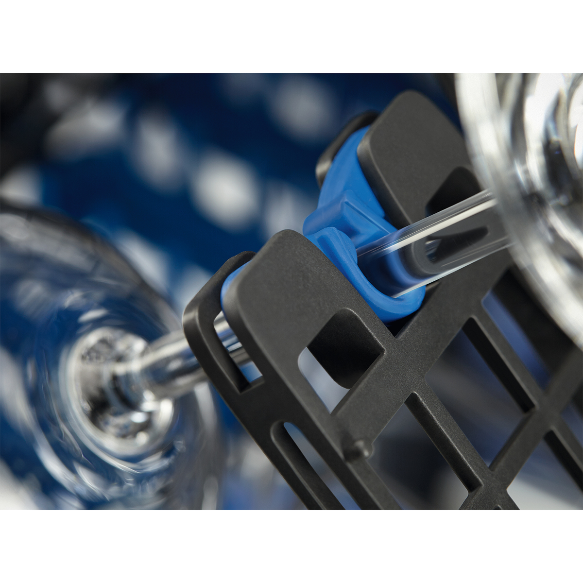 Zbliżenie uchwytu na szklanki w zmywarce, pokazujące szklankę i niebieskie uchwyty.