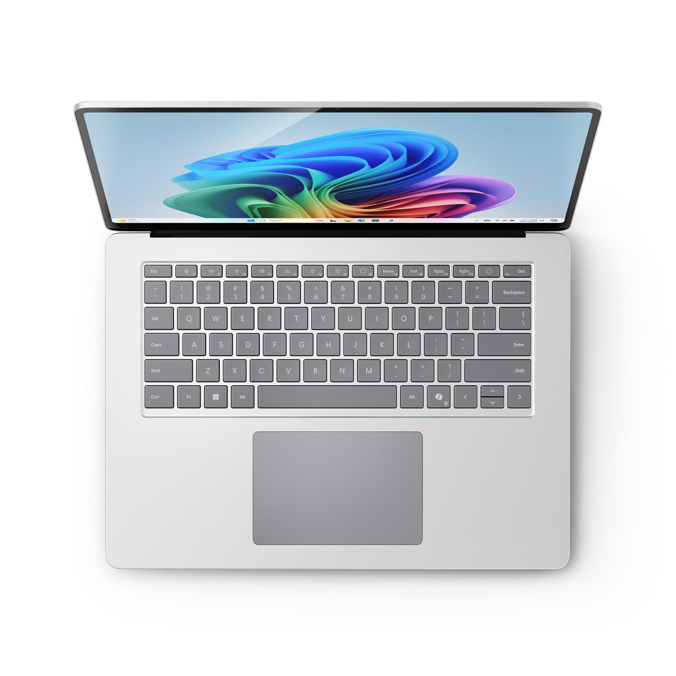 Laptop, widok z góry, otwarty z tęczowym abstrakcyjnym tłem na ekranie.