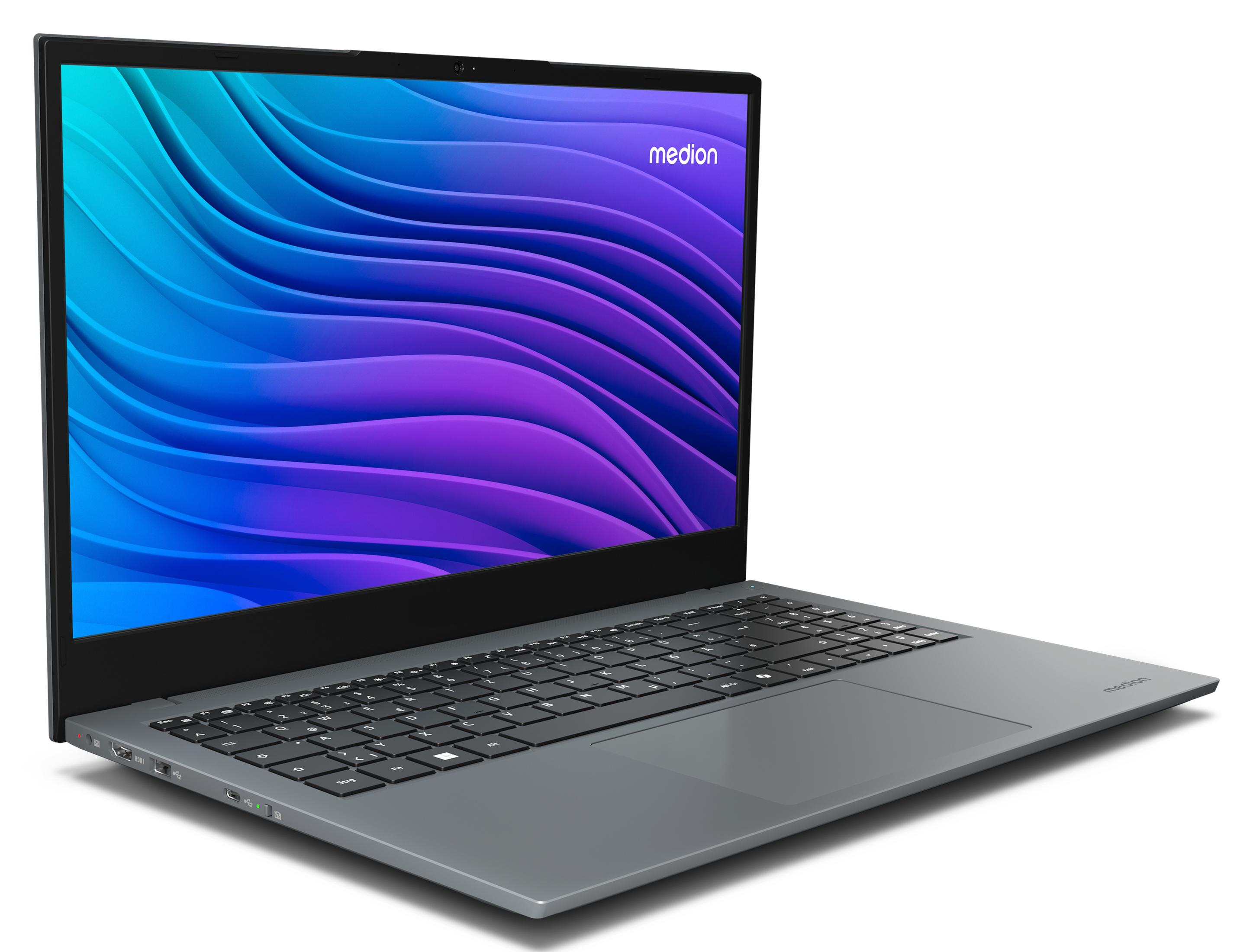 Szary laptop Medion, otwarty na biurku, wyświetlający niebiesko-fioletowy wzór fal.