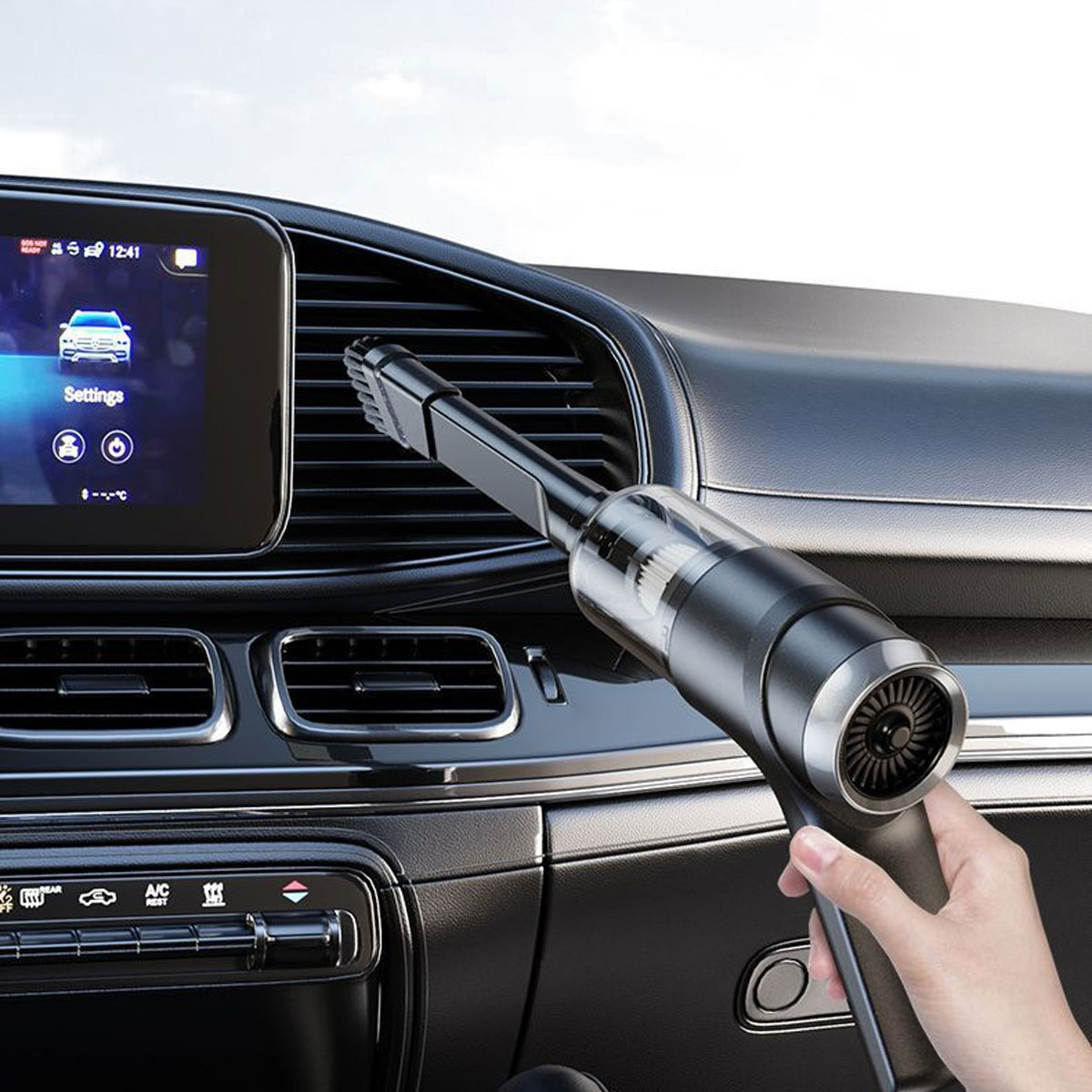 Hand hält einen schwarzen, kabellosen Staubsauger, der das Armaturenbrett eines Autos reinigt.