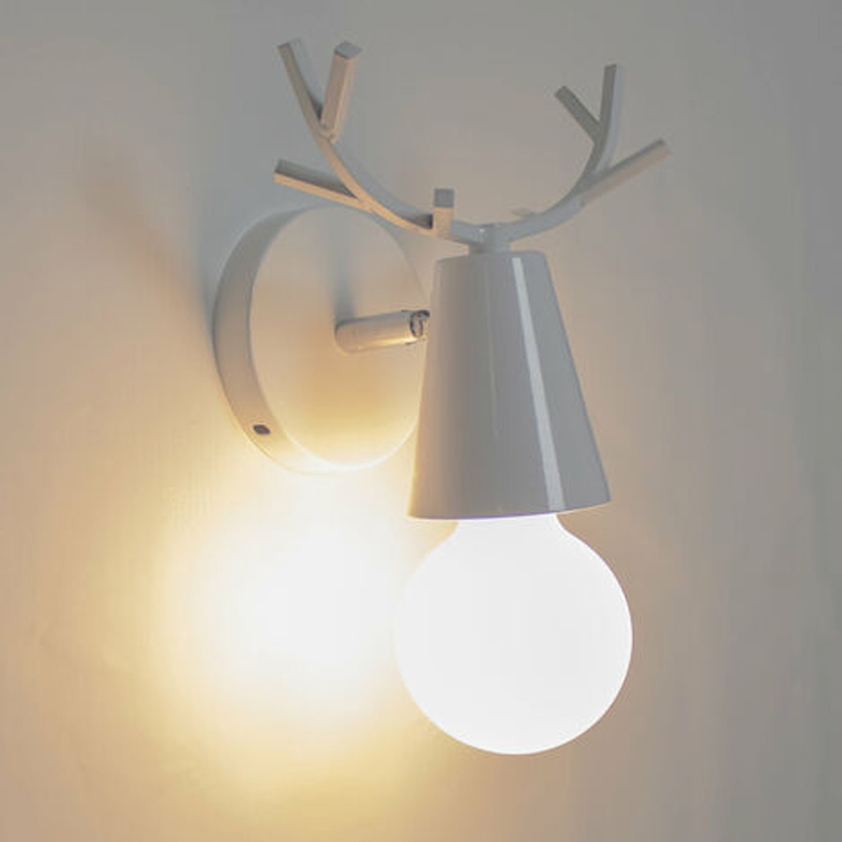 Weiße, hirschförmige Wandlampe mit Glühbirne.
