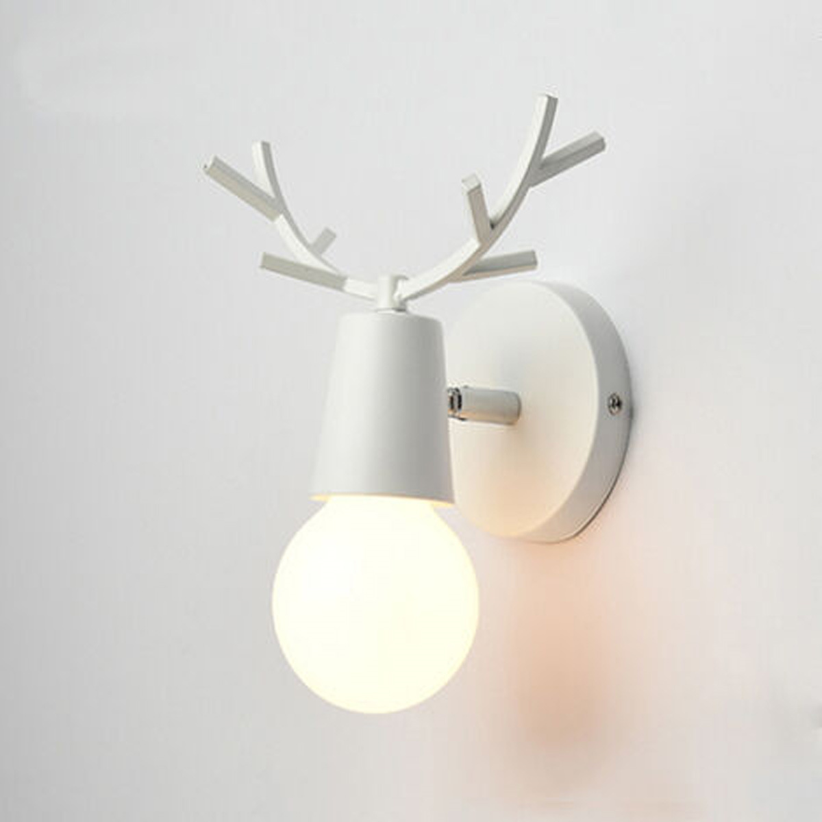 Weiße Wandlampe mit Rentiergeweih-Design. Der Hintergrund ist eine weiße Wand.