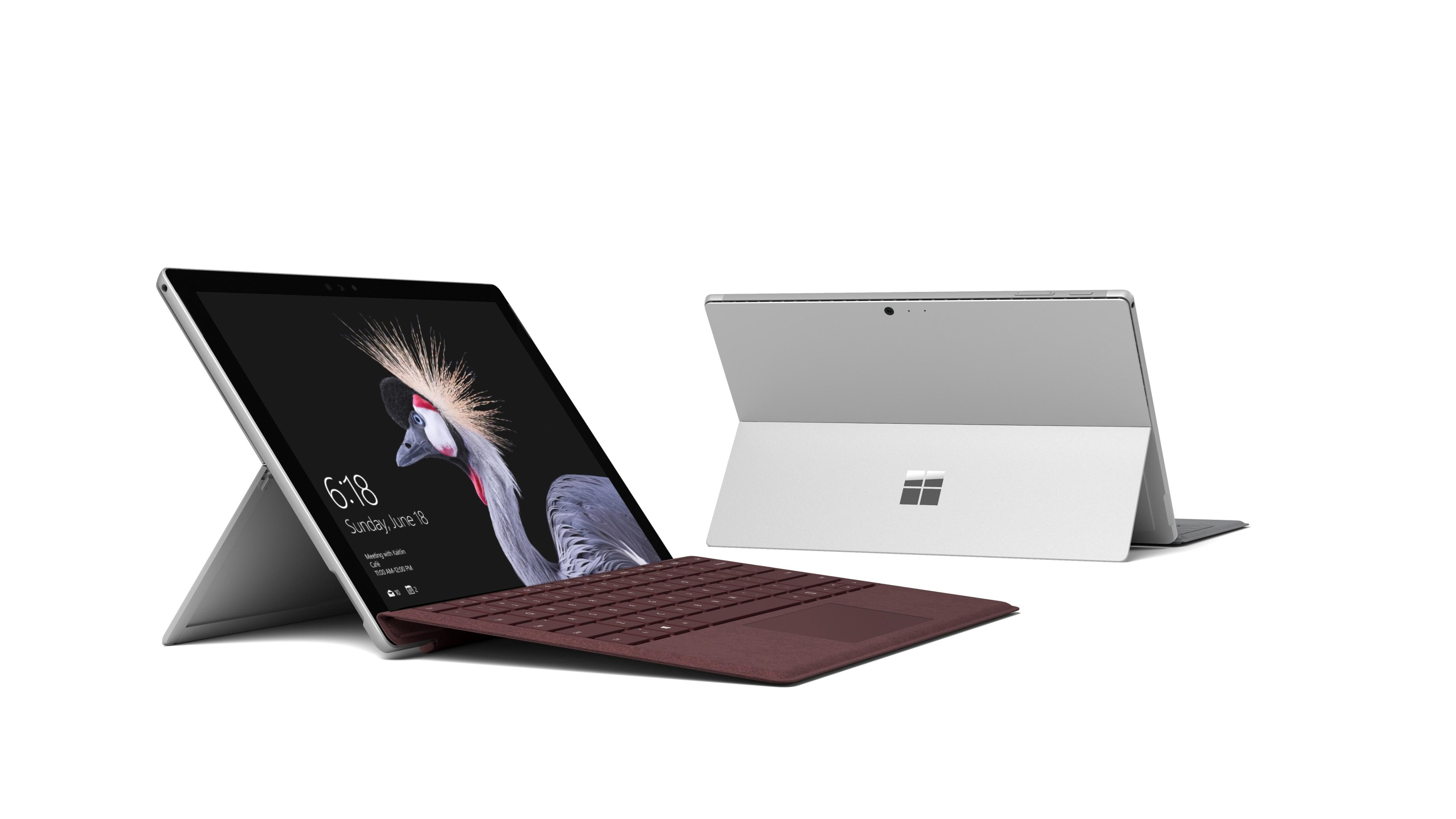 Zwei silberne Surface-Tablets mit Tastaturen. Eines ist geöffnet mit Vogelbildschirm.