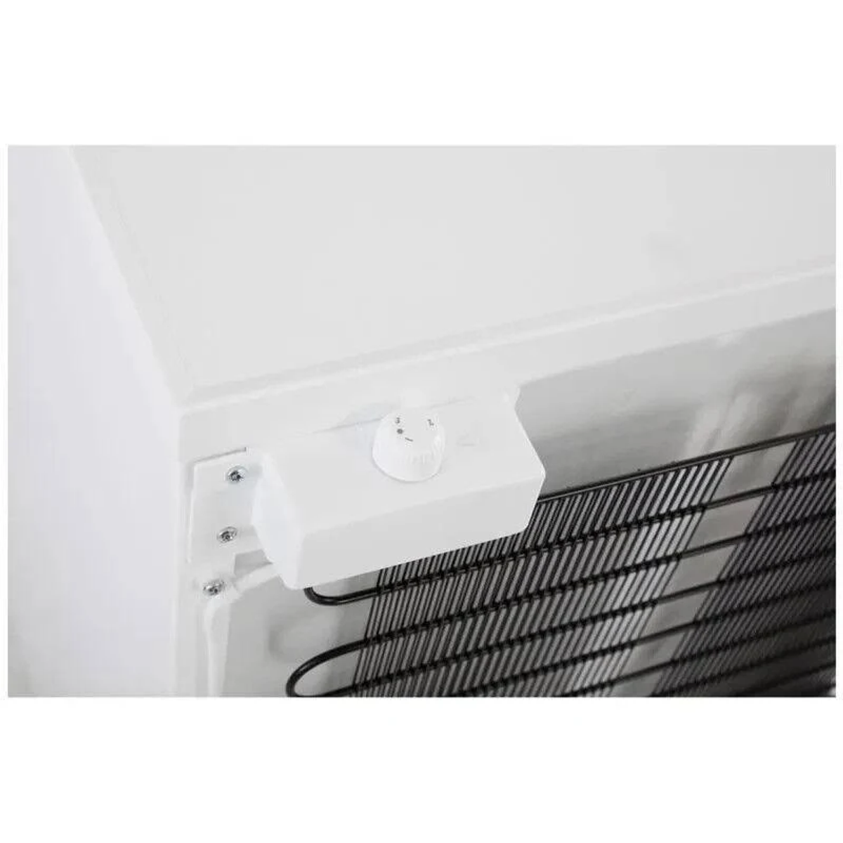Primo piano di un congelatore bianco. Visibile un pannello di controllo bianco con un quadrante. Bobine nere sullo sfondo.