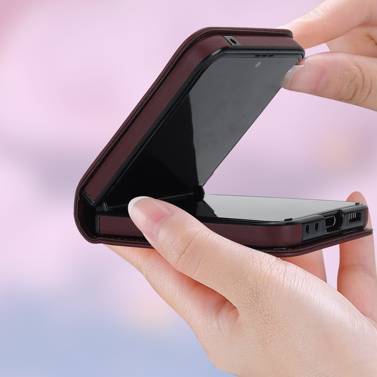 Manos sosteniendo una funda de teléfono granate, parcialmente abierta, revelando el teléfono en el interior.