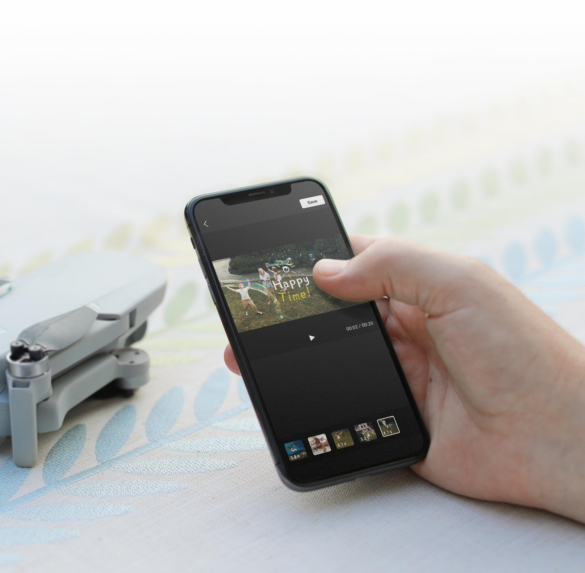 Eine Hand hält ein Smartphone mit einem Video. Eine Drohne liegt auf dem Tisch. Der Hintergrund ist unscharf.