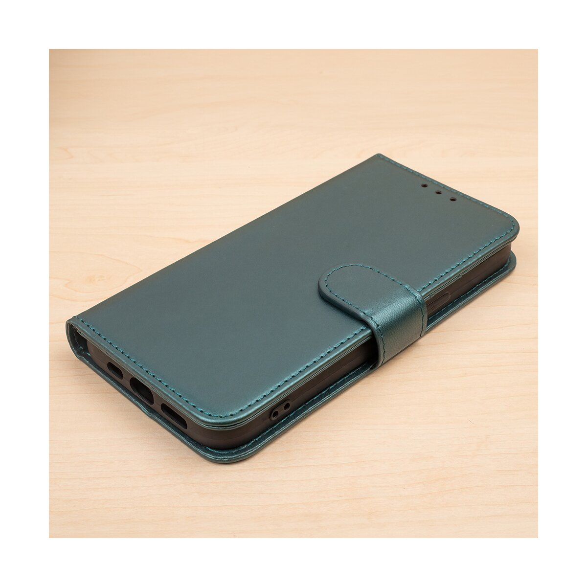 Una custodia per telefono verde con chiusura magnetica. È su una superficie di legno chiaro.