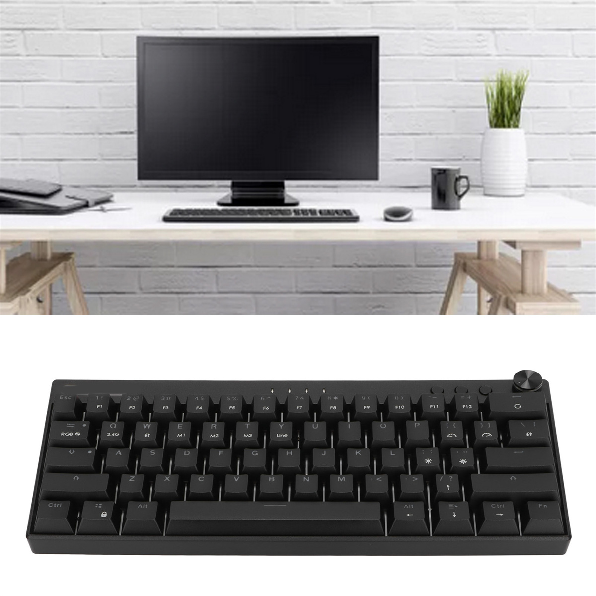 Eine Tastatur vor einem Monitor und einem Schreibtisch, mit weißer Backsteinmauer im Hintergrund.