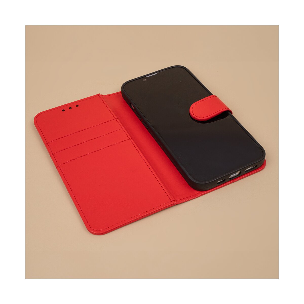 Custodia per telefono in pelle rossa aperta. C'è uno smartphone nero all'interno. La custodia è su una superficie color cuoio chiaro.