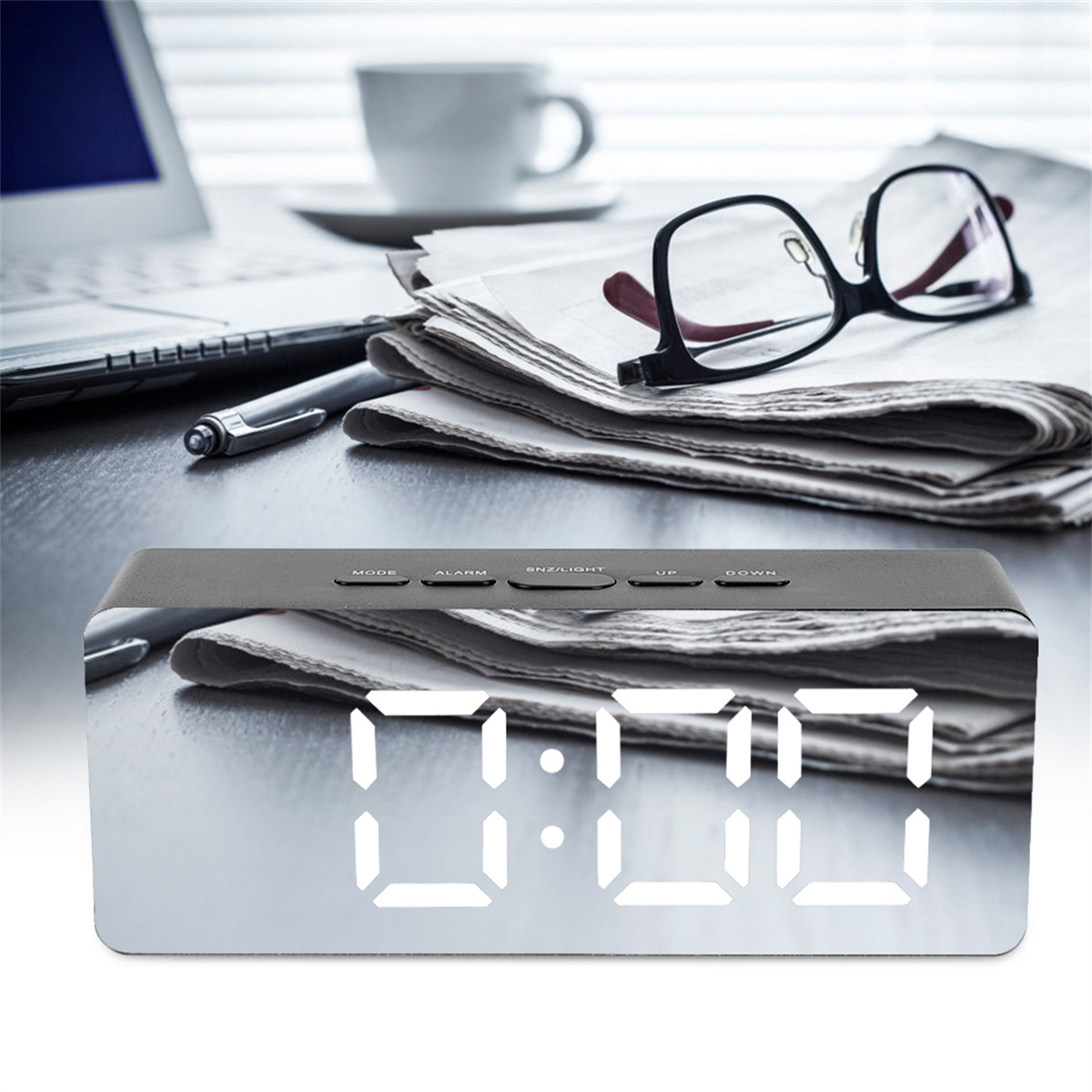 Ein digitaler Wecker mit Spiegelanzeige. Stift, Zeitung, Brille und eine Kaffeetasse sind in der Nähe.