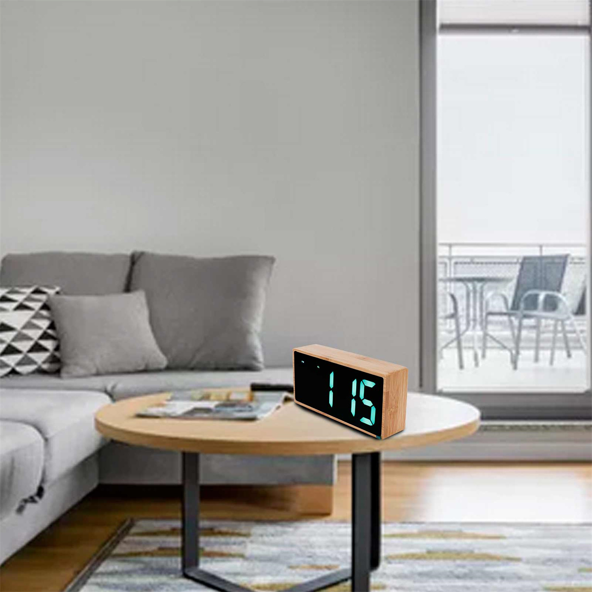 Eine Digitaluhr auf einem Tisch, die 1:15 anzeigt. Im Hintergrund ein Sofa und ein Fenster.