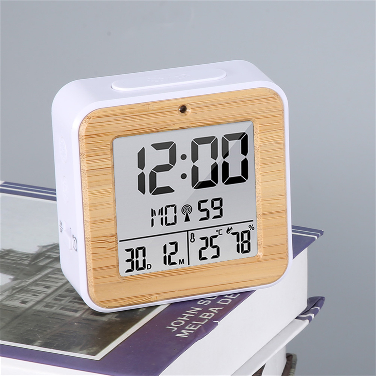 Eine digitale Uhr mit weißem und Holzrahmen. Zeigt Zeit, Datum, Temperatur und Luftfeuchtigkeit.