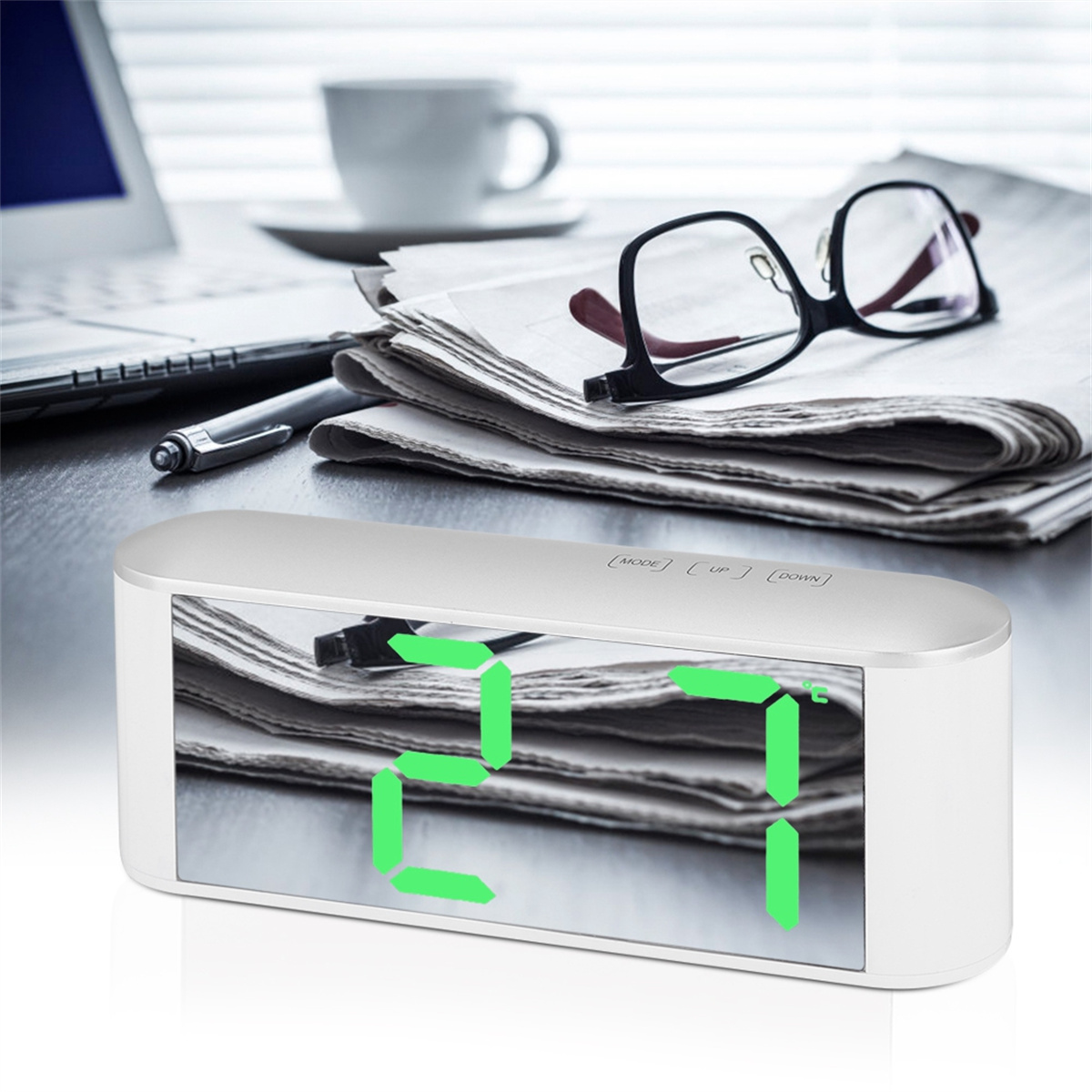 Silberner Wecker mit digitaler Anzeige. Brille und Stift auf dem Tisch.