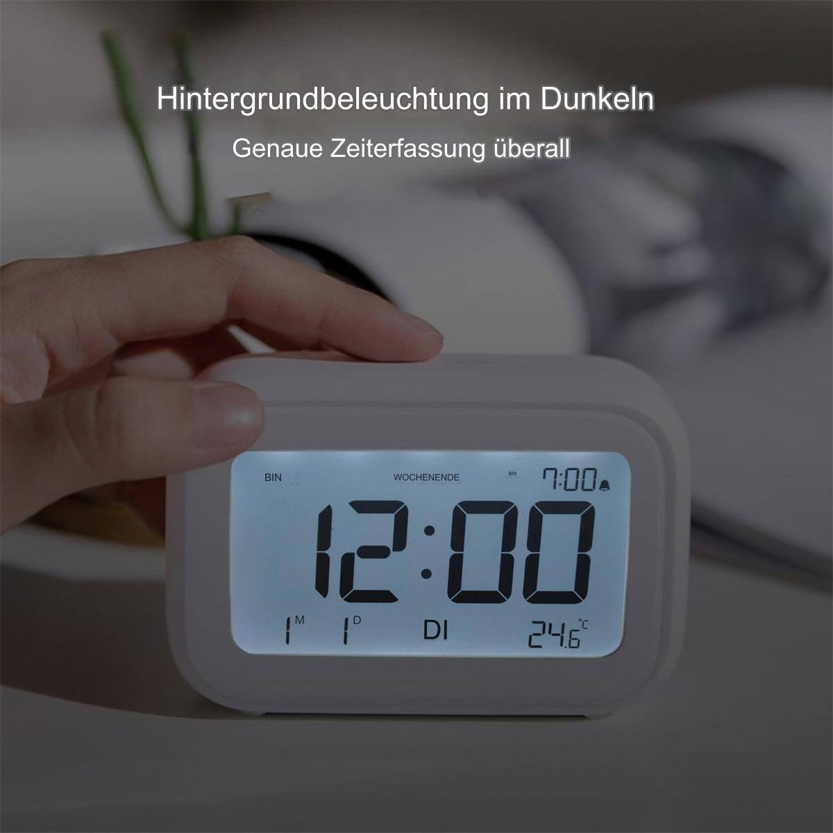 Hand in der Nähe eines digitalen Weckers mit 12:00 auf dem Bildschirm, der die Innentemperatur anzeigt.