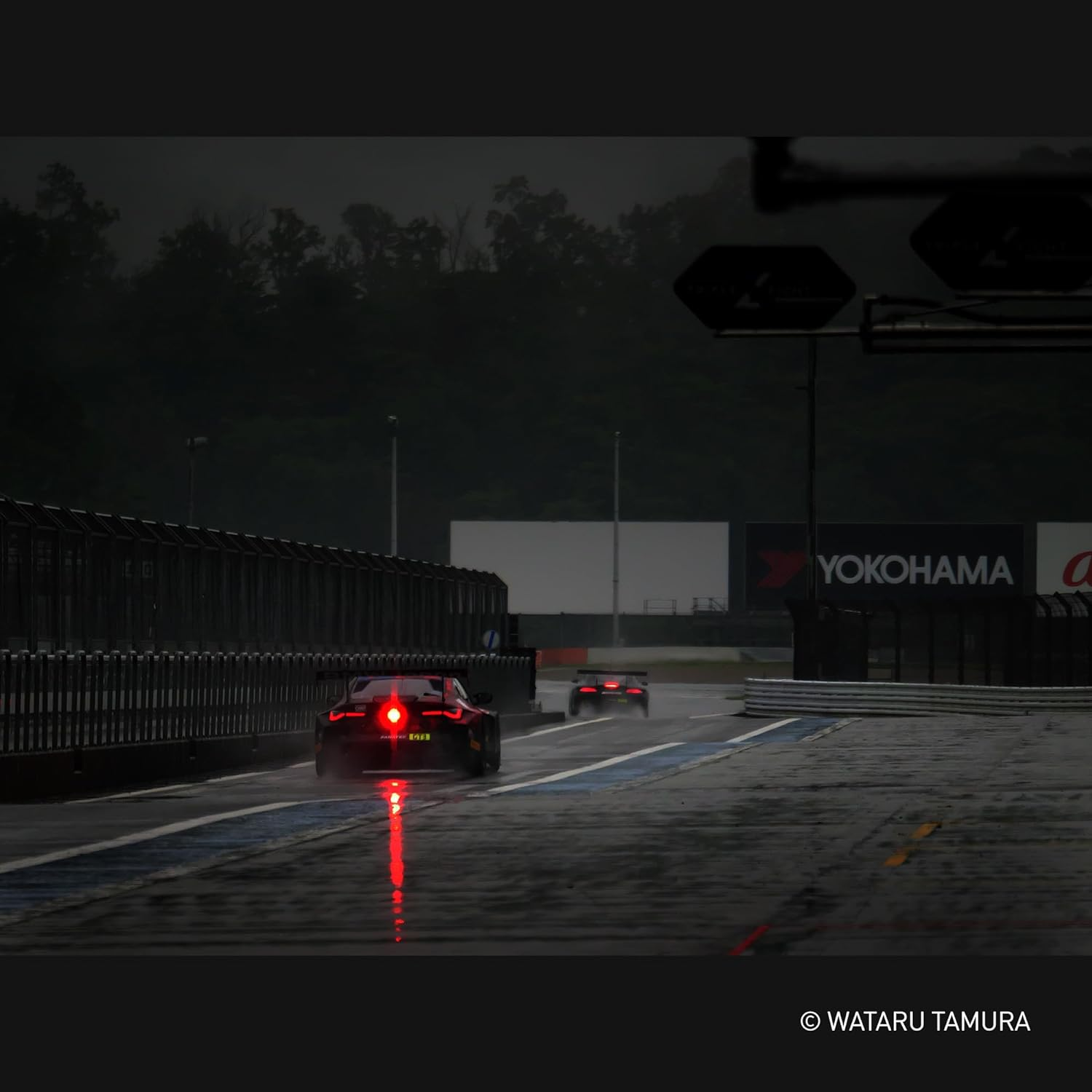 Samochody wyścigowe na mokrym torze. Czerwone światła tylne odbijają się w asfalcie. Znak Yokohama w tle.