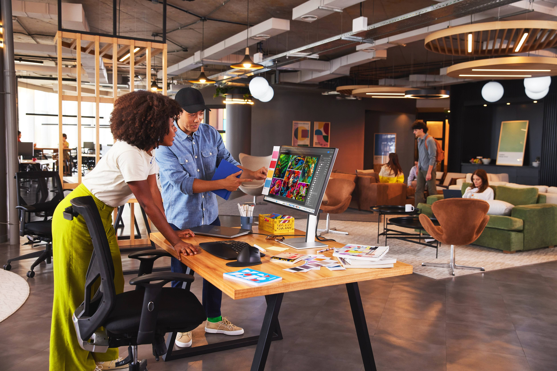 Scena biurowa z pracującymi ludźmi. Dwie osoby razem patrzą na ekran komputera.