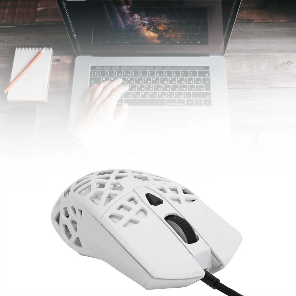 Weiße Gaming-Maus mit Wabenmuster. Eine Hand tippt auf dem Laptop.