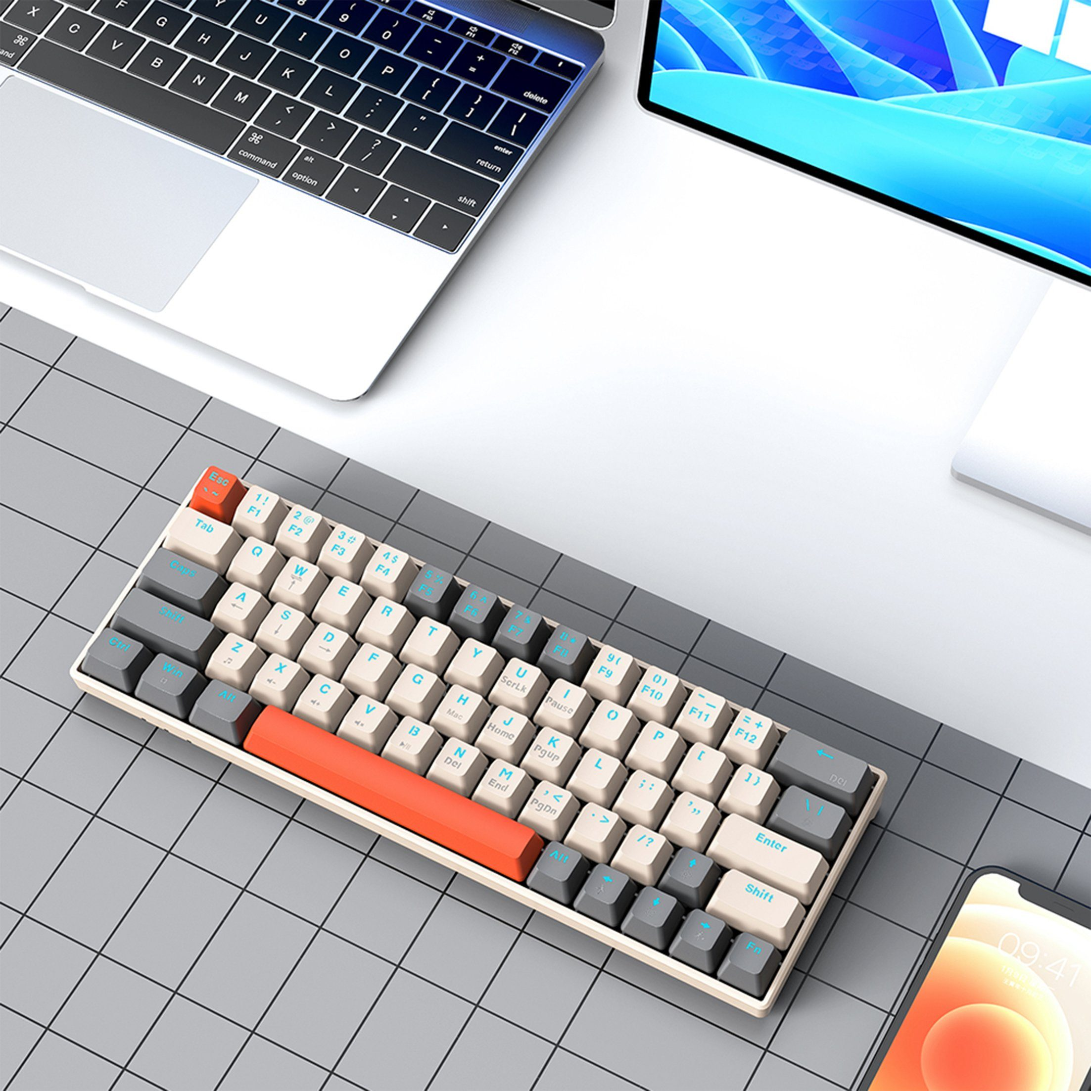 60% mechanische Tastatur auf einem Schreibtisch mit Computer und Telefon. Graue und orangefarbene Tasten.