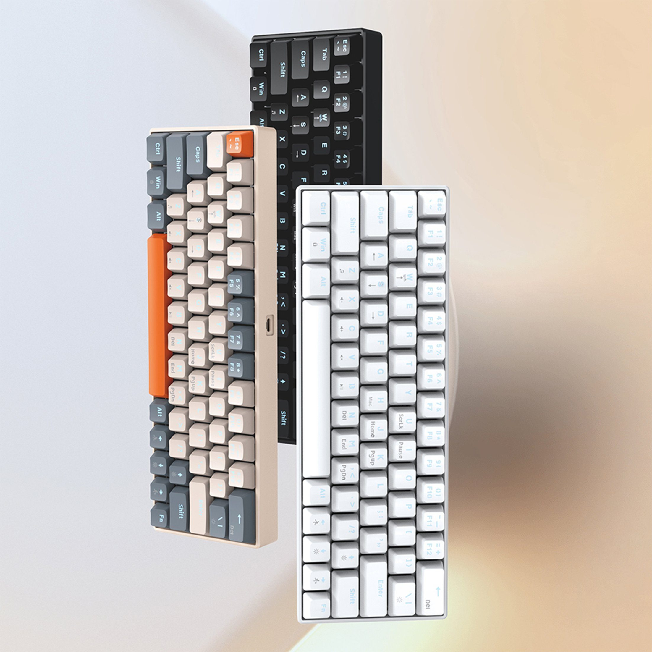 Drei farbige Tastaturen. Eine schwarz, eine weiß und eine beige mit orangefarbener Seite.