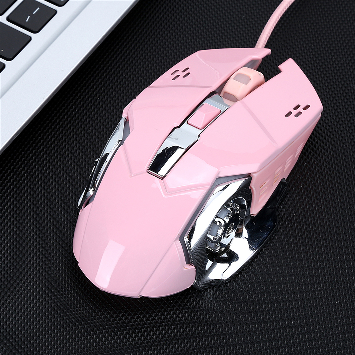 Eine pinke Computermaus wird auf einer schwarzen Oberfläche gezeigt. Es ist eine Gaming-Maus mit Chromakzenten.