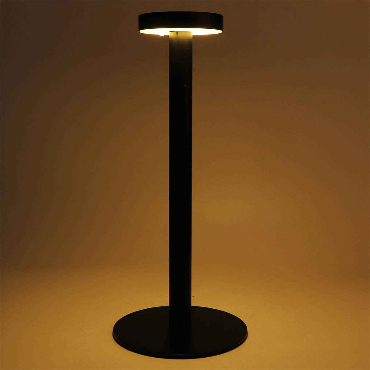 Eine schwarze Stehlampe mit rundem Sockel, beleuchtet von warmem Licht, auf braunem Hintergrund.