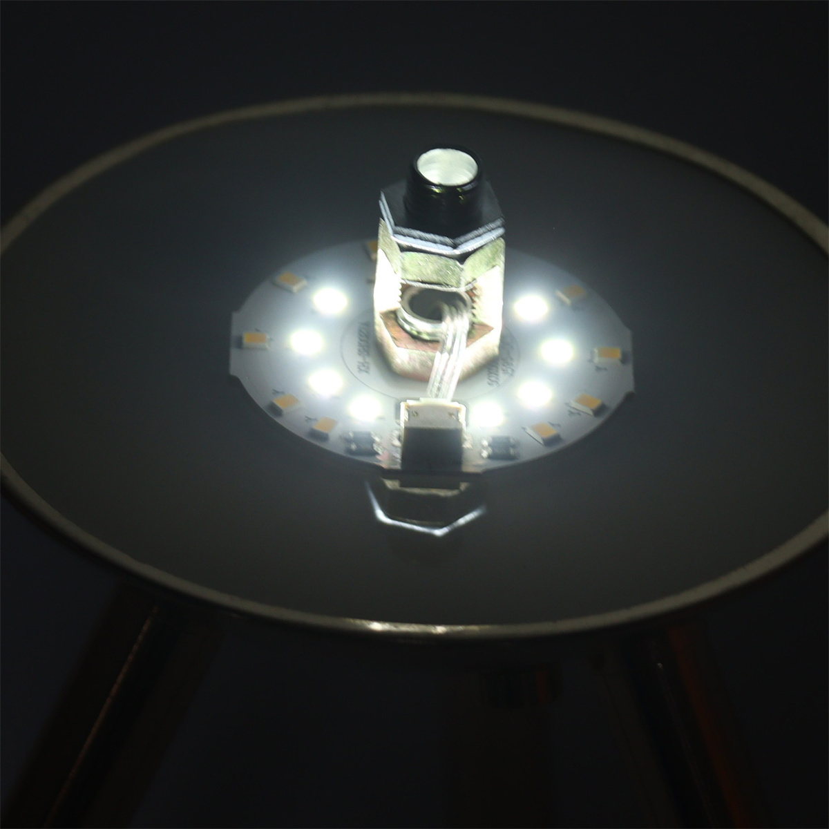LED-Licht mit Metallrahmen. Das Licht ist rund. Die Drähte sind mit dem Licht verbunden.