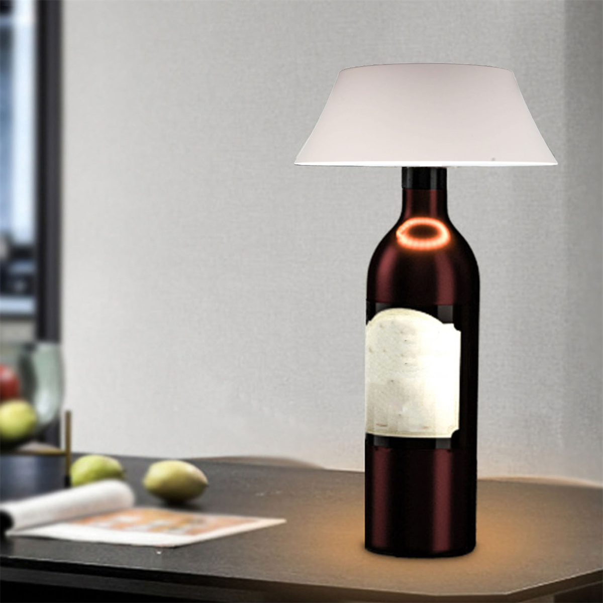 Lampe aus einer Weinflasche mit weißem Lampenschirm, auf einem Tisch.