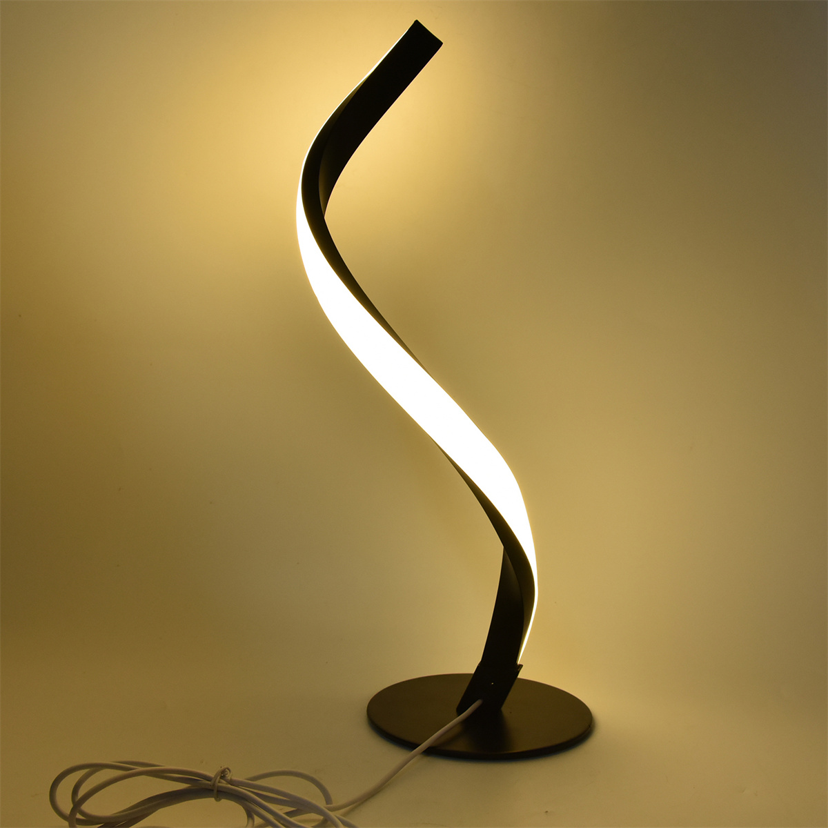 Schwarze geschwungene Schreibtischlampe mit weißem Licht, auf weißem Hintergrund.