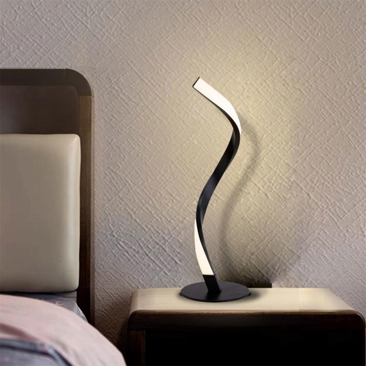 Moderne schwarz-weiße geschwungene Schreibtischlampe auf einem Nachttisch. Neutraler Hintergrund.