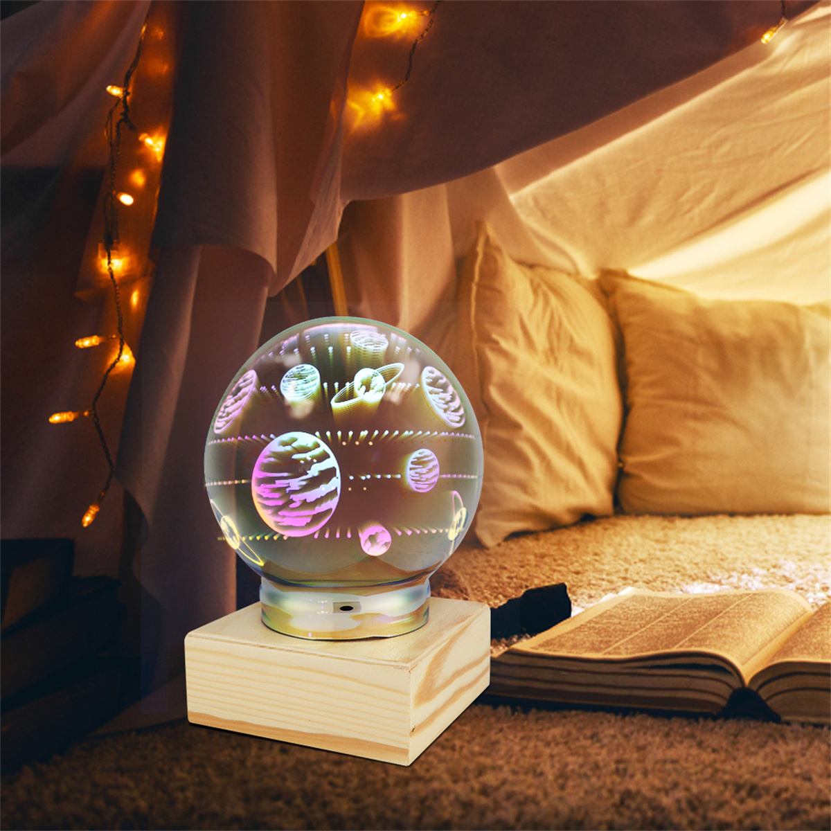Glaskugellampe mit Planeten im Inneren, auf Holzsockel. In einem Zelt mit sanfter Beleuchtung.