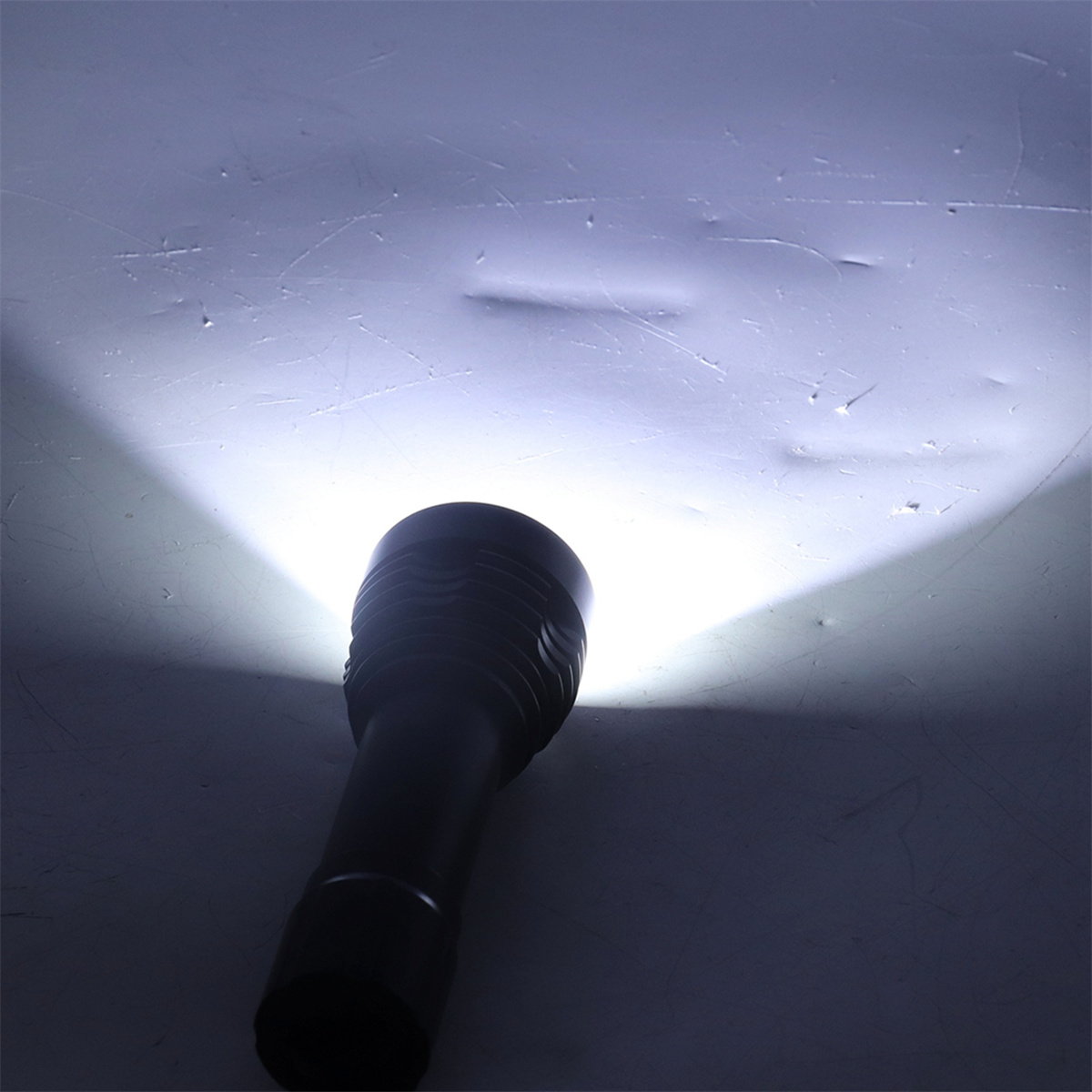 Schwarze Taschenlampe mit hellem weißem Strahl, der auf eine Oberfläche scheint.