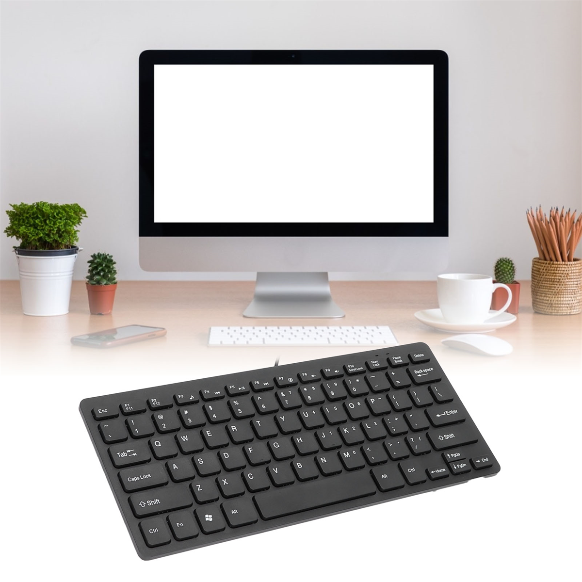 Eine schwarze Tastatur liegt auf einem Schreibtisch vor einem Computermonitor.