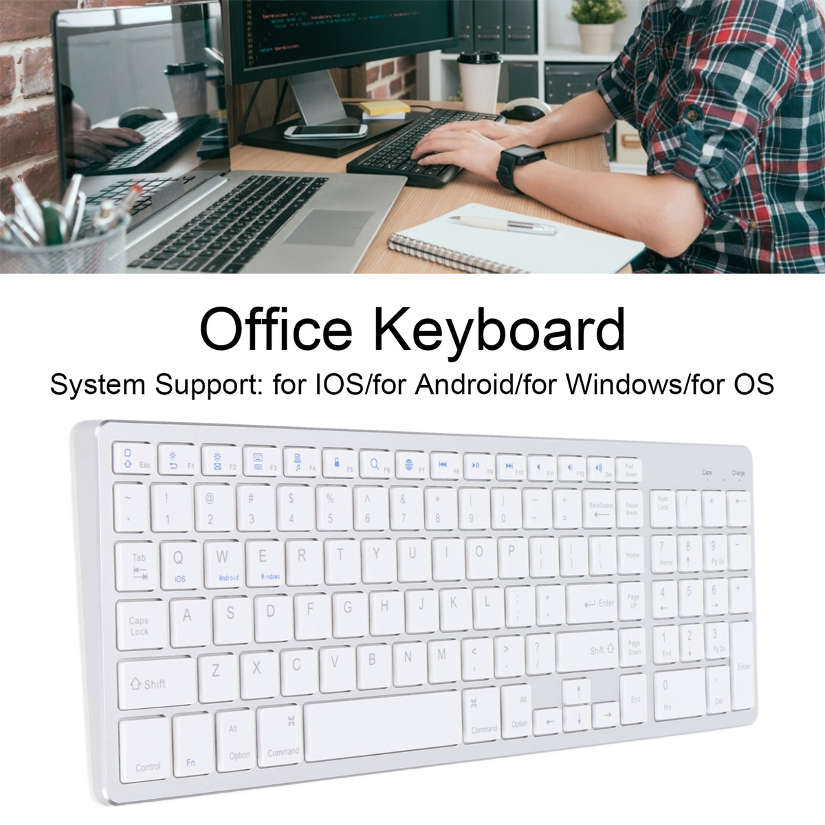 Eine weiße Tastatur mit schwarzen Tasten liegt unter einer Person, die auf einem Laptop tippt. Ein zweiter Monitor ist im Hintergrund.