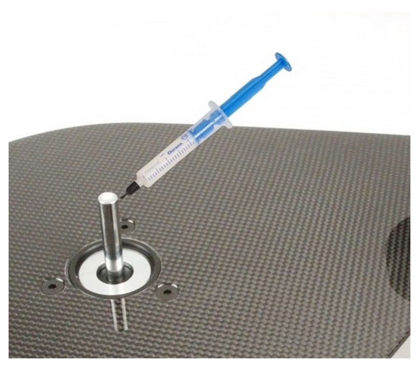 Zbliżenie strzykawki wstrzykującej płyn do metalowego cylindra na białym tle.