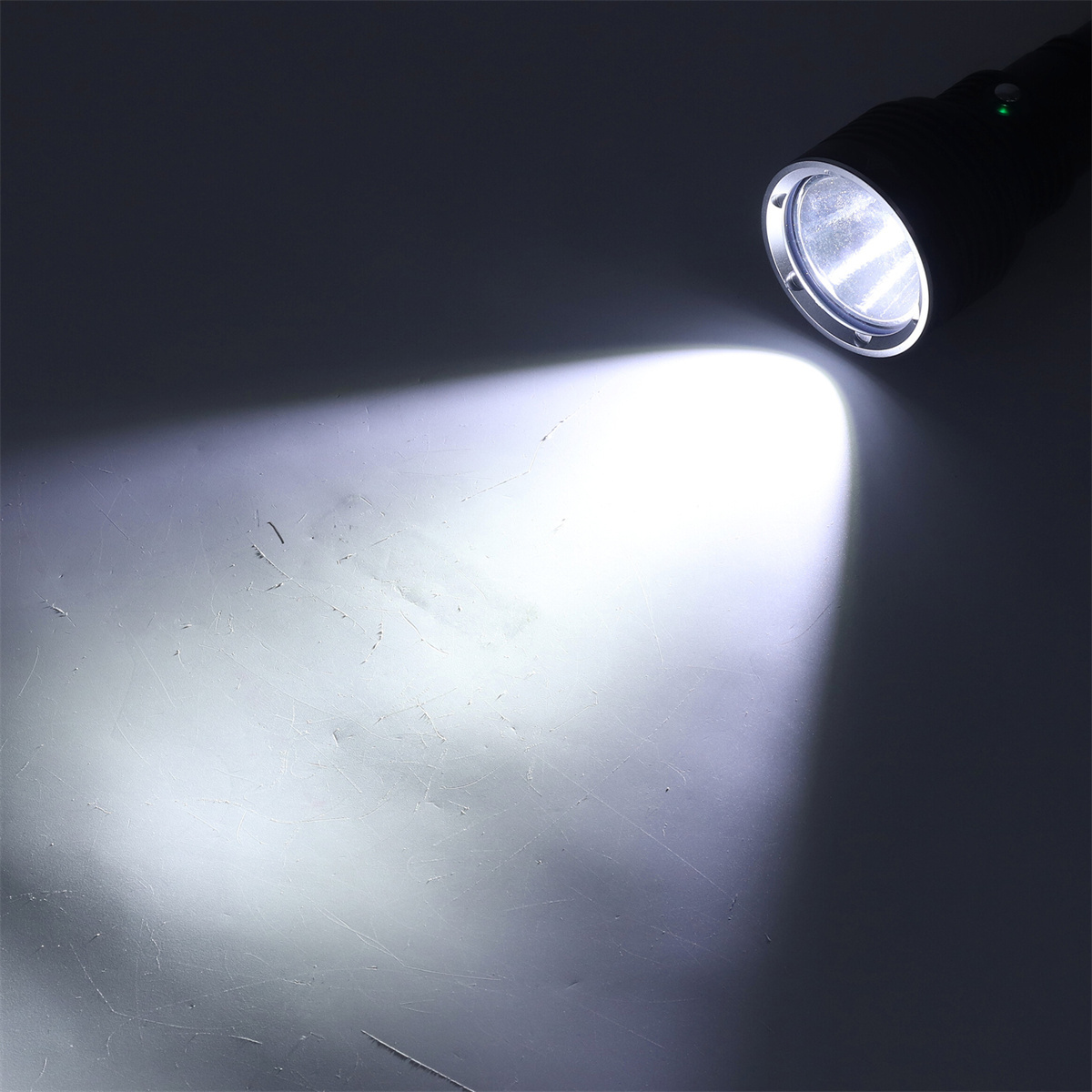 Schwarze Taschenlampe mit hellem weißem Lichtstrahl, der eine graue Oberfläche beleuchtet.
