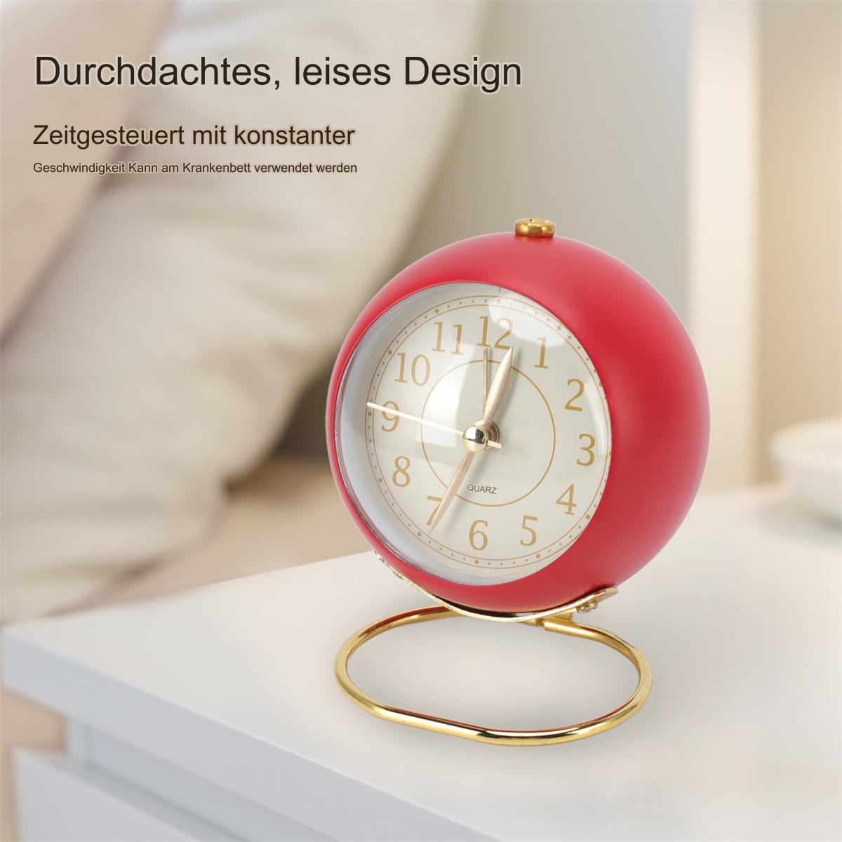 Ein roter, kugelförmiger Wecker mit goldenem Ständer, auf weißer Oberfläche. Die Zeit ist 11:07.