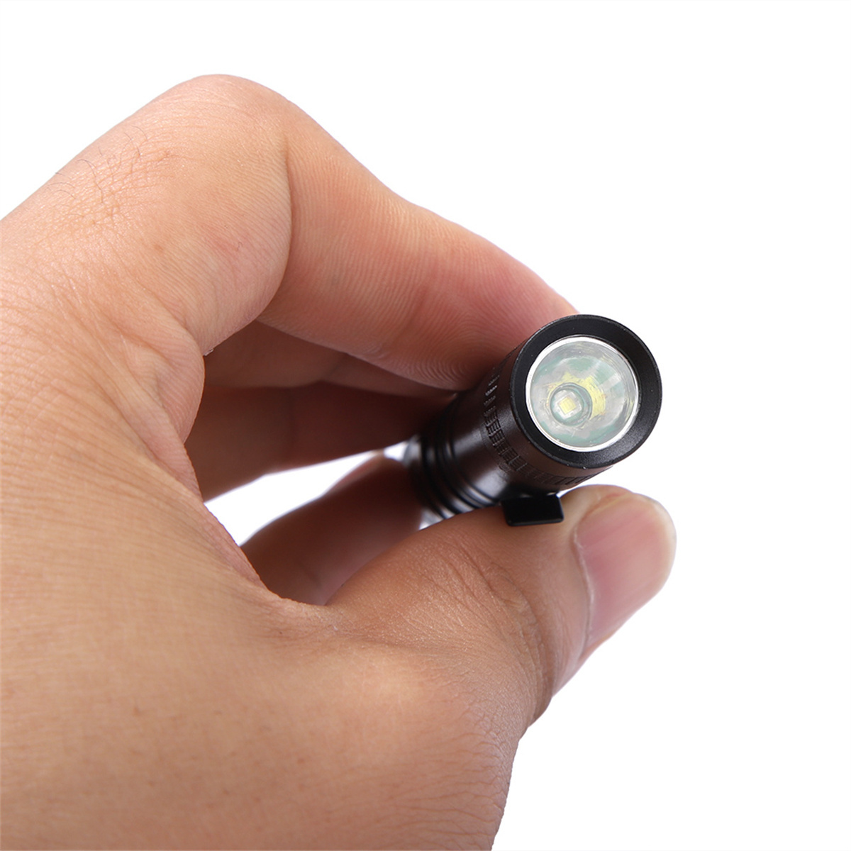 Eine Hand, die eine kleine, schwarze Taschenlampe mit hellem, weißem Licht hält.