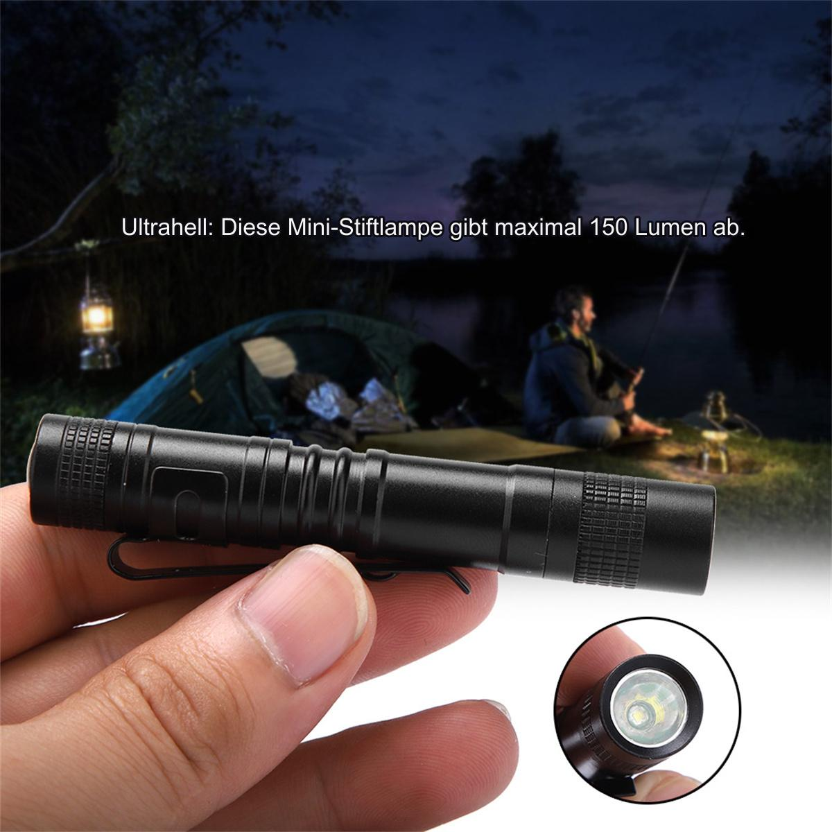Person hält kleine schwarze Taschenlampe, dunkler Hintergrund. Zelt und Angelnder im Hintergrund.