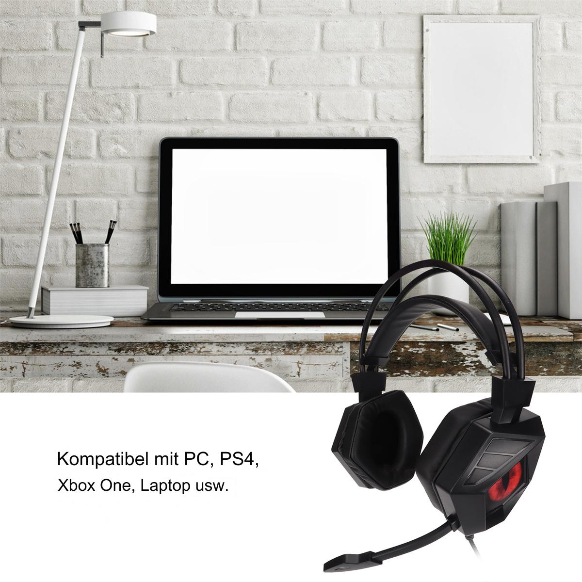 Schwarzes Gaming-Headset auf einem Schreibtisch mit Laptop, Lampe und Büchern vor einer weißen Backsteinmauer.