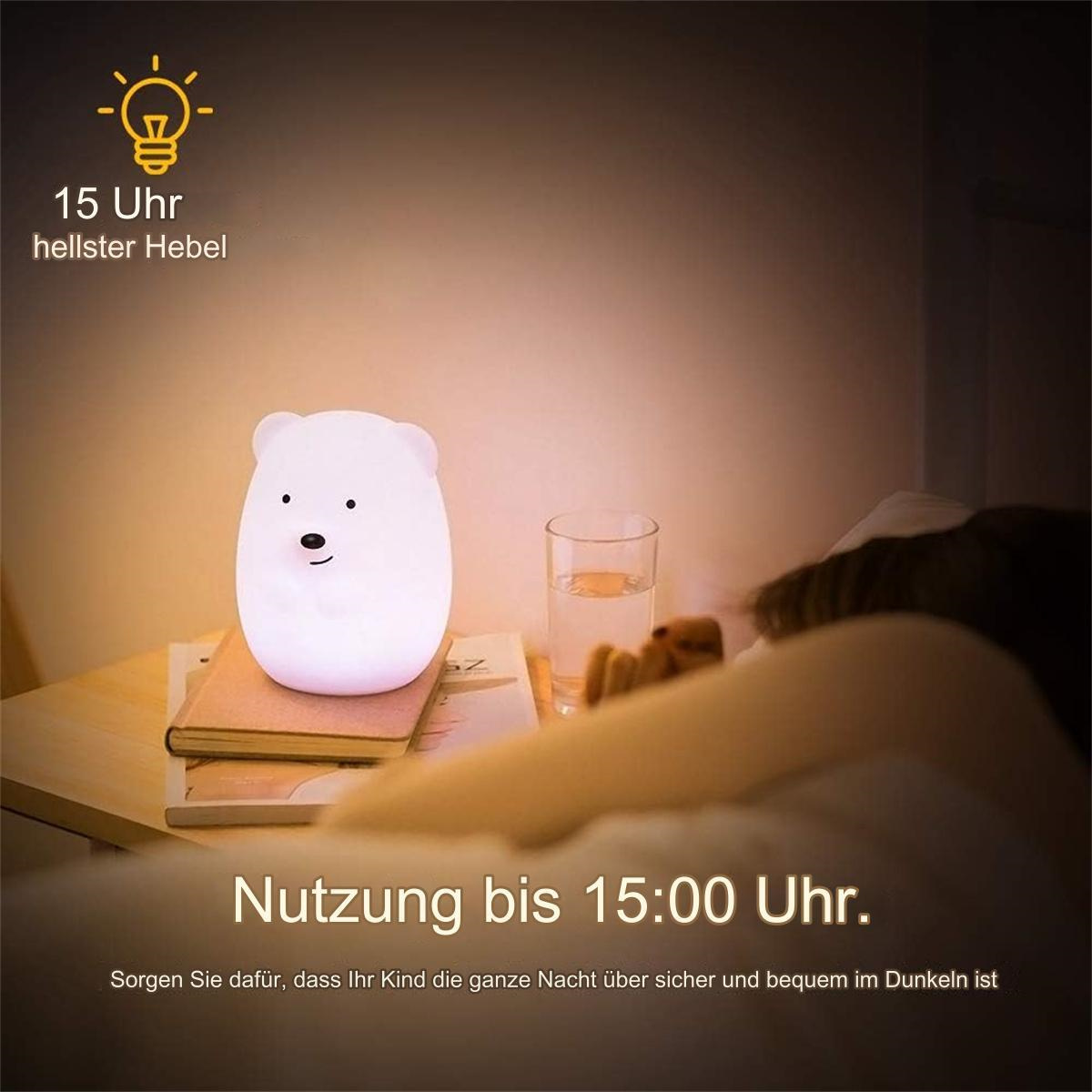 Weißer Bären-Lampe auf einem Nachttisch mit Büchern und einem Glas Wasser. Text auf Deutsch.