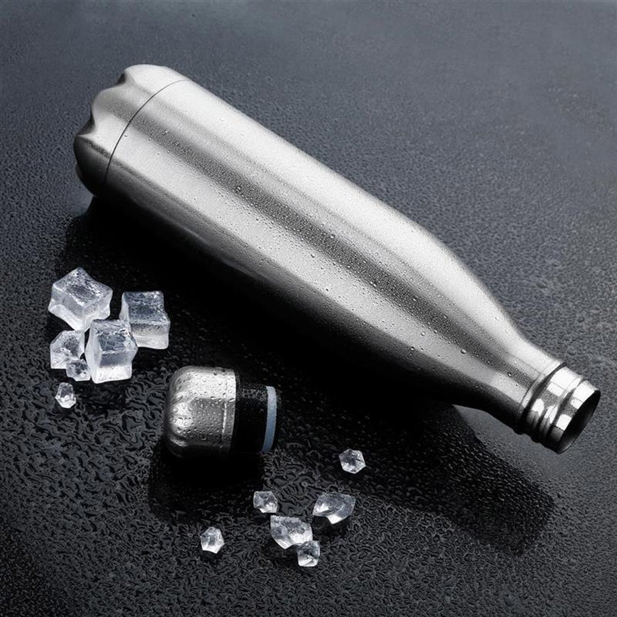 Edelstahl-Wasserflasche mit Eiswürfeln daneben, auf einer nassen, schwarzen Oberfläche.