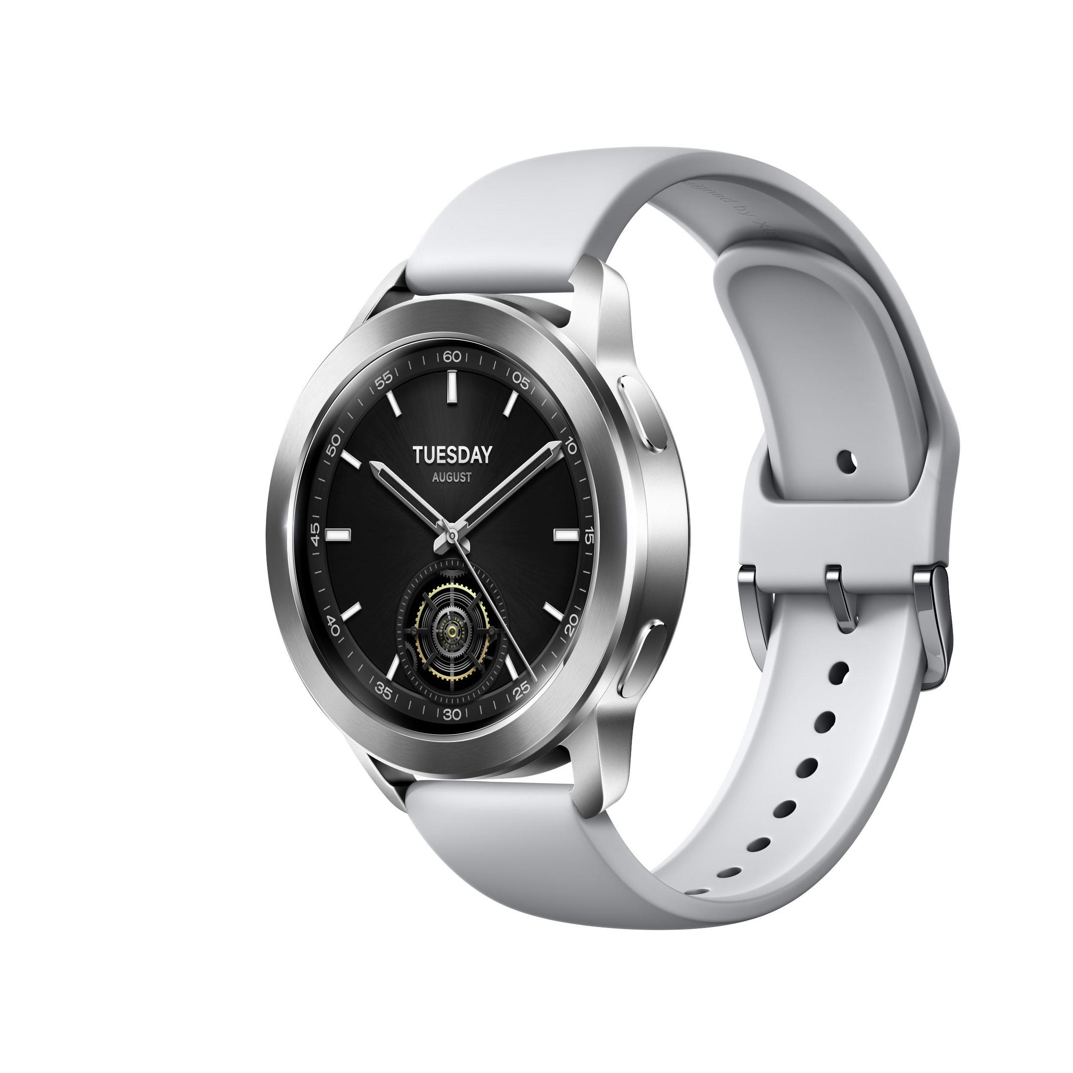 Eine silberne Smartwatch mit schwarzem Zifferblatt und weißem Armband. Die Zeit zeigt Dienstag, August.