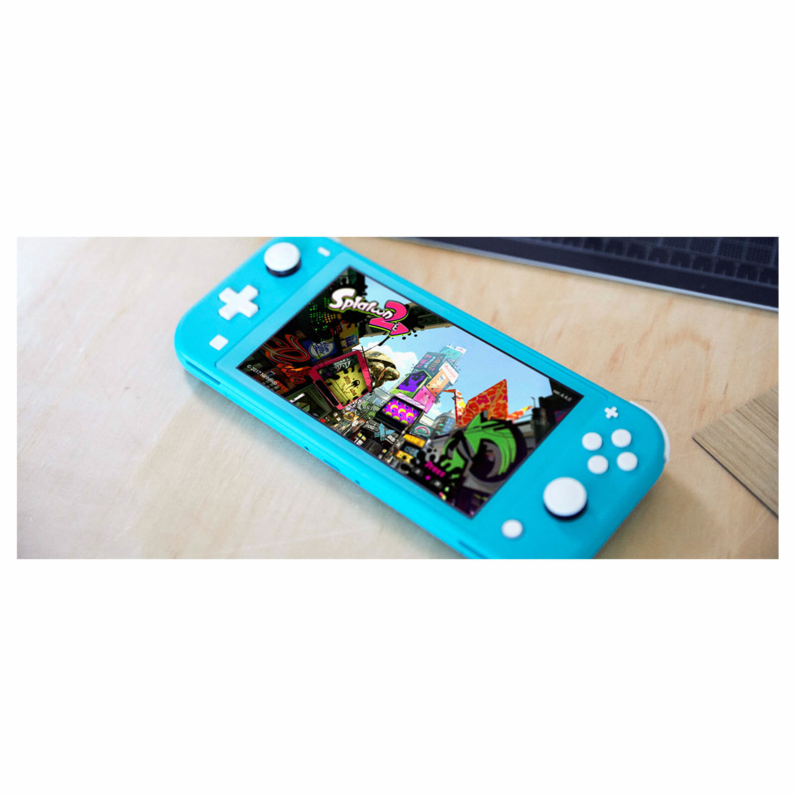 Eine türkis Nintendo Switch Lite Konsole, die das Spiel Splatoon 2 auf einer Holzoberfläche zeigt.